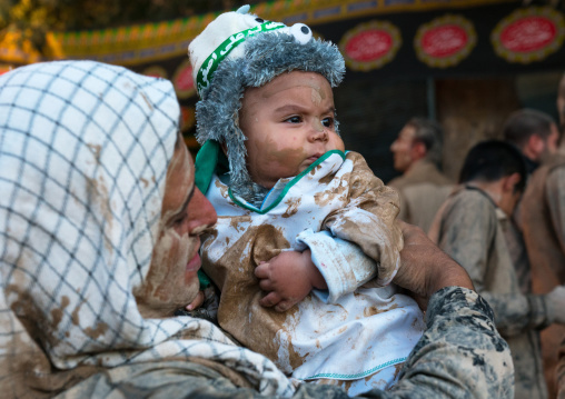 Iranian shiite muslim father rubbing mud on his baby during the Kharrah Mali ritual to mark the Ashura day, Lorestan Province, Khorramabad, Iran