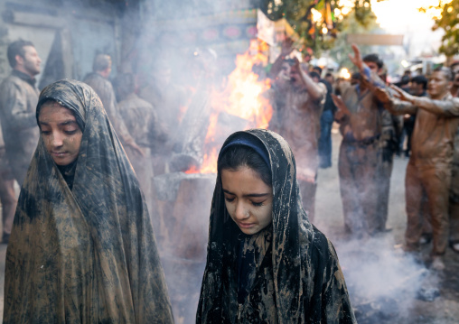 Iranian shiite muslim men and women gather around a bonfire after rubbing mud on their clothes during the Kharrah Mali ritual to mark the Ashura day, Lorestan Province, Khorramabad, Iran