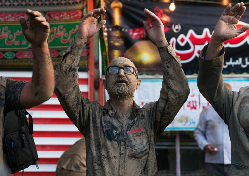 Iranian shiite muslim men praying after rubbing mud on their clothes during the Kharrah Mali ritual to mark the Ashura ceremony, Lorestan Province, Khorramabad, Iran
