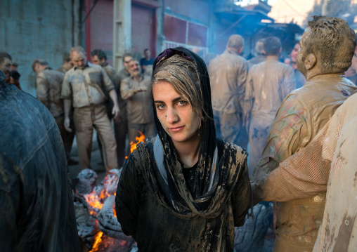 An iranian shiite muslim woman stands in front a bonfire after rubbing mud on her chador during the Kharrah Mali ritual to mark the Ashura day, Lorestan Province, Khorramabad, Iran