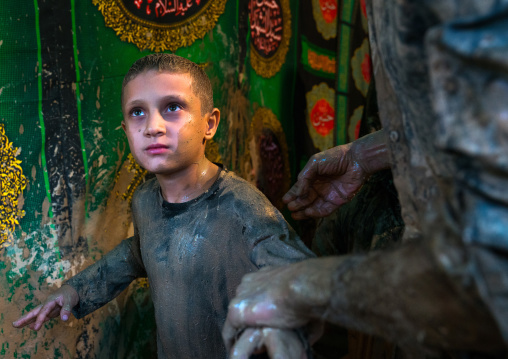 Iranian shiite muslim boy after rubbing mud on his body during the Kharrah Mali ritual to mark the Ashura day, Lorestan Province, Khorramabad, Iran