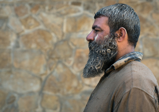 Iranian shiite muslim man after rubbing mud on his clothes during the Kharrah Mali ritual to mark the Ashura ceremony, Lorestan Province, Khorramabad, Iran