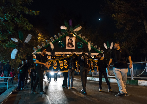 An iranian man carrying an alam is helped by shiite muslim mourners to keep his balance during Muharram, Central County, Theran, Iran