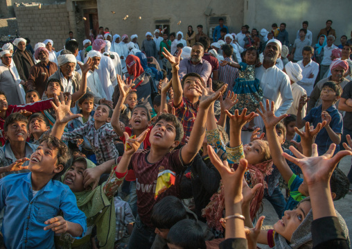 children catching sweets thrown from the house roof during a wedding ceremony, Qeshm Island, Salakh, Iran