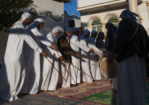men dressed in white dancing with sticks during a wedding ceremony, Hormozgan, Bandar-e Kong, Iran
