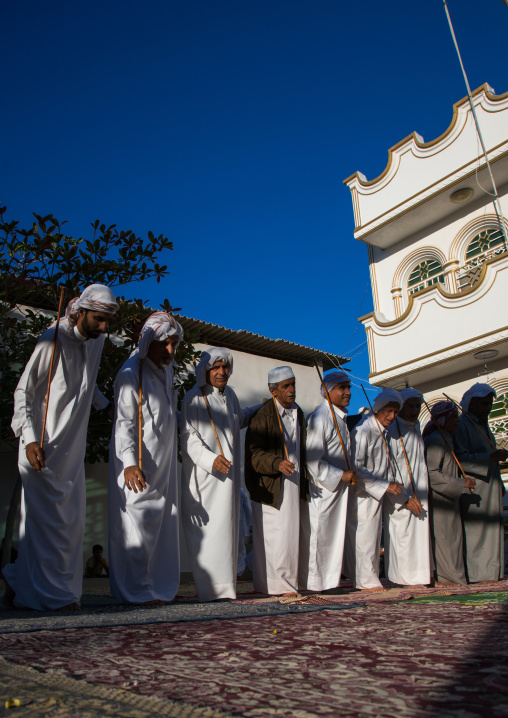 men dressed in white dancing with sticks during a wedding ceremony, Hormozgan, Bandar-e Kong, Iran