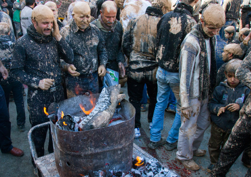 Iranian Shiite Muslim Men Covered In Mud Searching For Heat In Front Of A Fire During Ashura Day, Kurdistan Province, Bijar, Iran