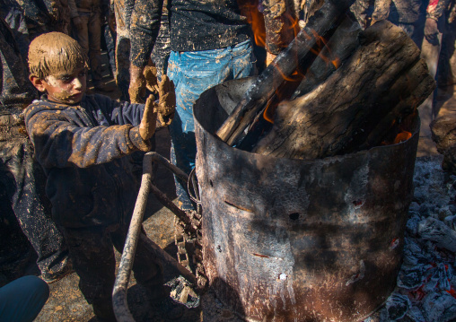 Iranian Shiite Muslim Boy Covered In Mud Searching For Heat In Front Of A Fire During Ashura Day, Kurdistan Province, Bijar, Iran