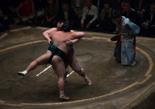 Two sumo wrestlers fighting at the ryogoku kokugikan arena, Kanto region, Tokyo, Japan