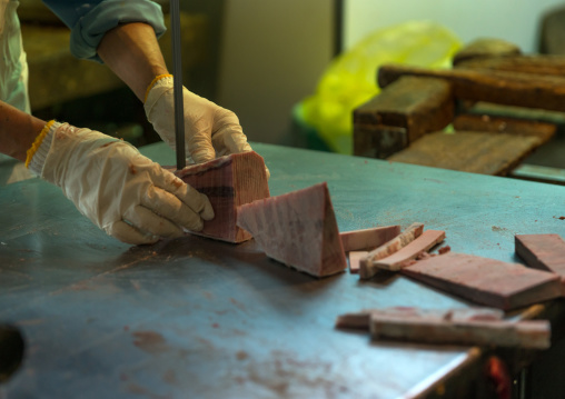 Worker cutting tuna in tsukiji fish market, Kanto region, Tokyo, Japan