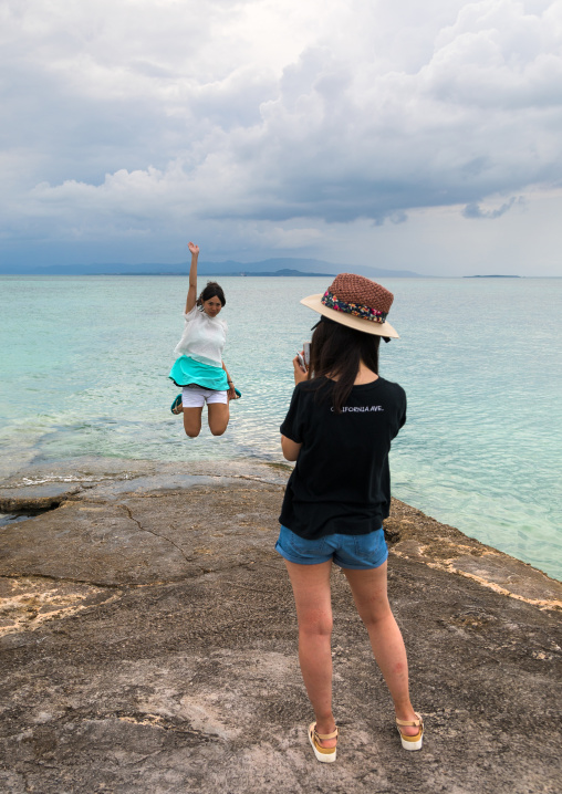 Japanese tourist jumping for a picture on nishi pier, Yaeyama Islands, Taketomi island, Japan