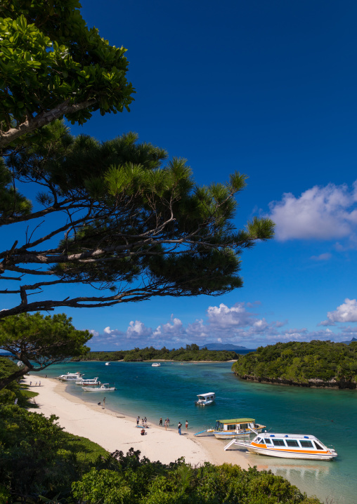 Glass bottom boats in the tropical lagoon beach with clear blue water and white sand in Kabira bay, Yaeyama Islands, Ishigaki, Japan