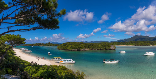 Glass bottom boats in the tropical lagoon beach with clear blue water and white sand in Kabira bay, Yaeyama Islands, Ishigaki, Japan