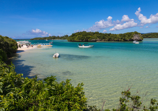 Glass bottom boats in the tropical lagoon beach with clear blue water and white sand in Kabira bay, Yaeyama Islands, Ishigaki, Japan