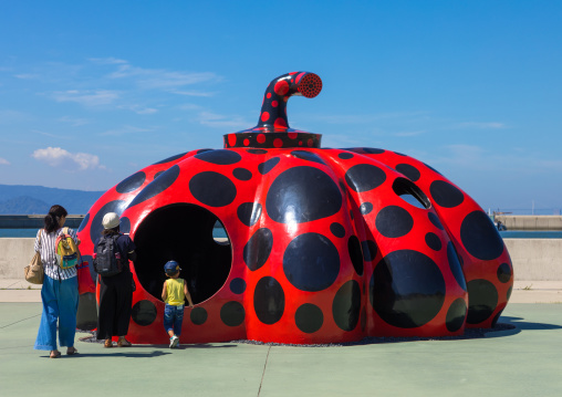 Family in front of Yayoi Kusama red pumpkin, Seto Inland Sea, Naoshima, Japan