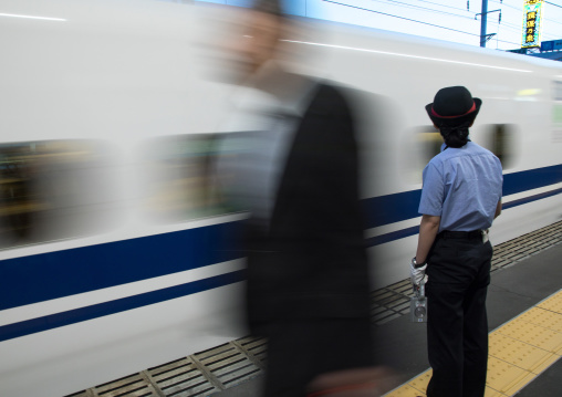Japanese female station master in front of a Shinkansen train in a station, Hypgo Prefecture, Himeji, Japan