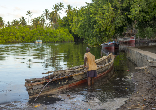 Fisherman taking care of his dhow moored along coastline, Lamu county, Matondoni, Kenya