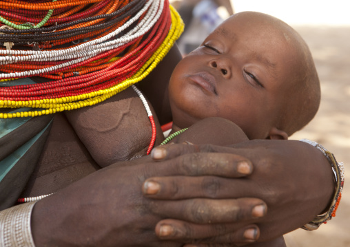 Rendille tribeswoman holding her sleeping baby, Marsabit district, Ngurunit, Kenya