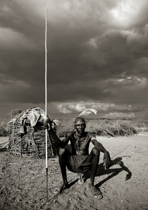 Portrait of a Pokot tribe man sit on his wooden pillow holding a spear, Baringo County, Baringo, Kenya