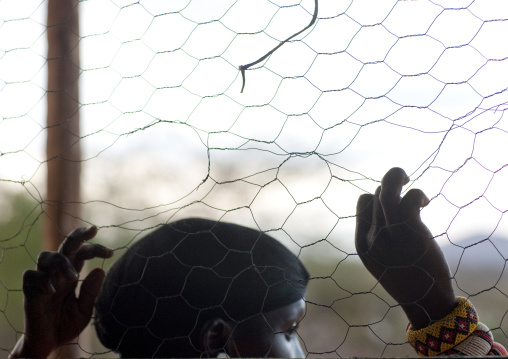 Samburu tribe young man looking thru a fence, Samburu County, Maralal, Kenya