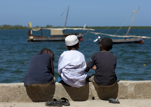 Three muslim boys chatting alongside the dockside, Lamu County, Lamu, Kenya