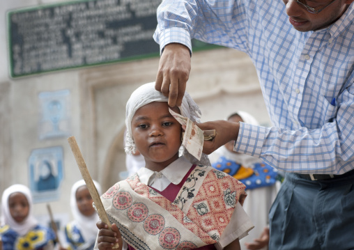 Man putting bank note under young girl's veil during Maulid festival, Lamu County, Lamu, Kenya