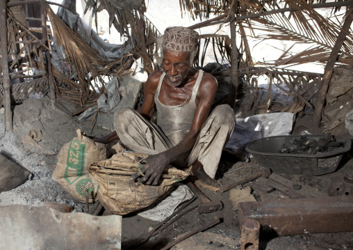 Blacksmith sweating while he forges nails, Lamu County, Lamu, Kenya