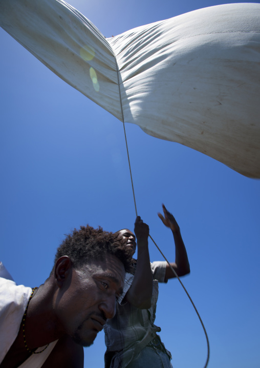 Man raising the sail on a dhow, Lamu County, Lamu, Kenya