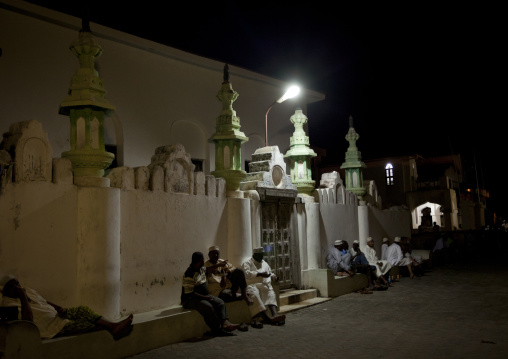 Men sitting outside a mosque at night during Maulid festival, Lamu County, Lamu, Kenya