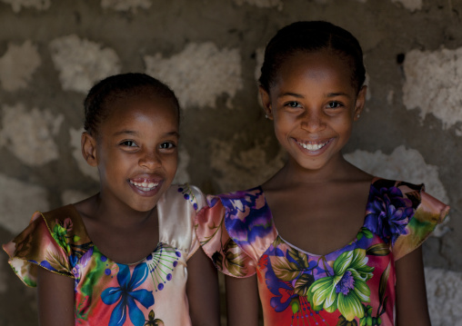 Kenyan girls in colorful dresses against a wall, Lamu County, Lamu, Kenya