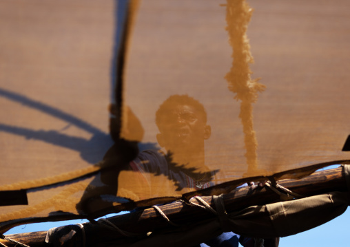 Man taking care of the sail on a dhow, Lamu County, Lamu, Kenya