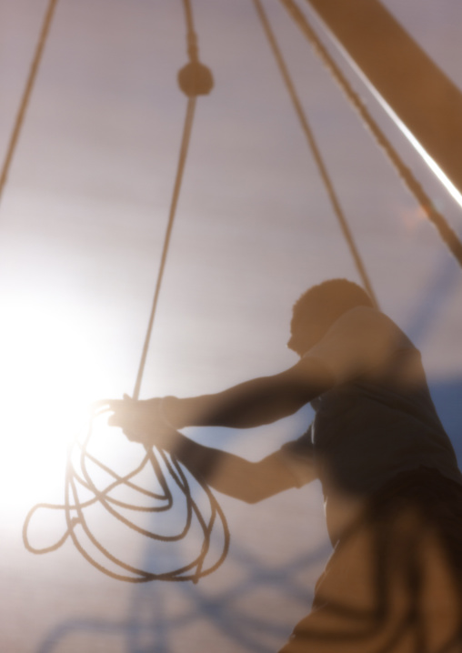Man rising the sail of a dhow, Lamu County, Lamu, Kenya