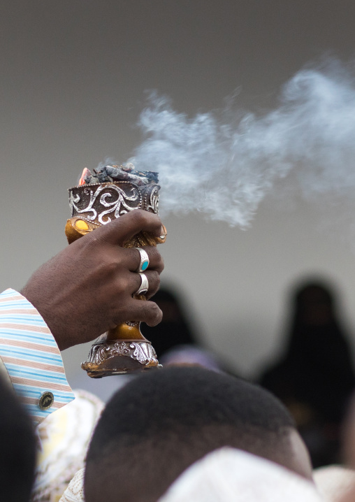 Sunni muslim man spreading insence with a censer during the maulidi festivities in the street, Lamu county, Lamu town, Kenya
