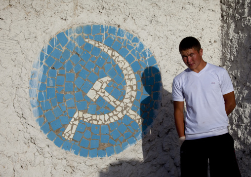 Young Man In Front Of A Mosaic Of The Hammer And Sickle, Kochkor, Kyrgyzstan