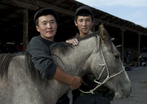 Two Young Men Holding A Horse At The Animal Market Of Kochkor, Kyrgyzstan