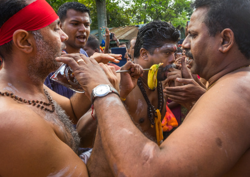 A Devotee Cheek Is Pierced With A Giant Skewer By A Priest At Thaipusam Hindu Festival At Batu Caves, Southeast Asia, Kuala Lumpur, Malaysia