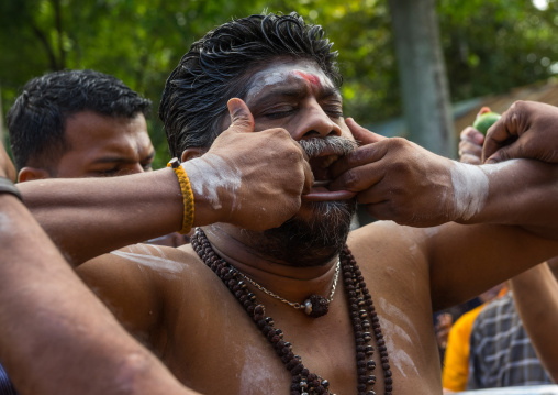 A Devotee Cheek Is Pierced With A Skewer By A Priest At Thaipusam Hindu Festival At Batu Caves, Southeast Asia, Kuala Lumpur, Malaysia
