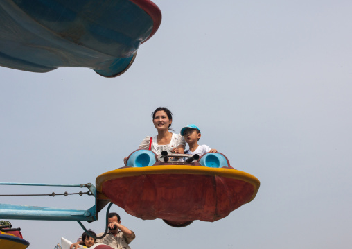 North Korean people having fun on a flying saucer attraction in Taesongsan funfair, Pyongan Province, Pyongyang, North Korea