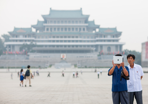 North Korean men using an ipad on Kim ii-sung square, Pyongan Province, Pyongyang, North Korea