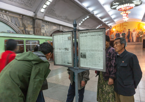 North Korean people reading the offical state newspaper in a subway station, Pyongan Province, Pyongyang, North Korea