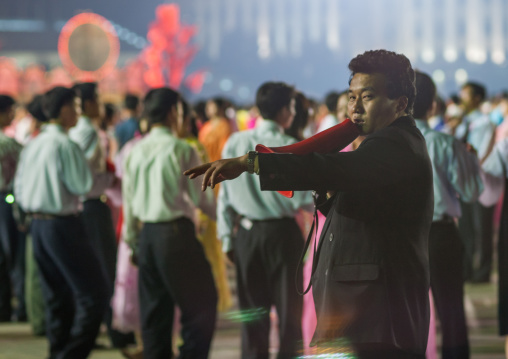 North Korean man with a megaphone giving orders to students dancing to celebrate april 15 the birth anniversary of Kim Il-sung, Pyongan Province, Pyongyang, North Korea
