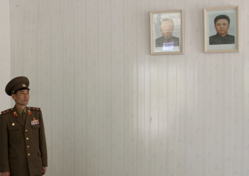 North Korean soldier in the Demilitarized Zone in front of the official portraits of the Dear Leaders, North Hwanghae Province, Panmunjom, North Korea
