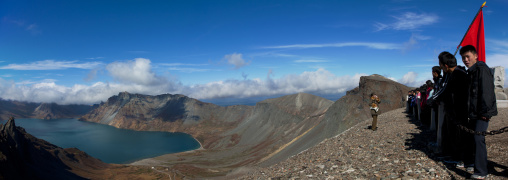 Group of students with red flag in front of lake at mount Paektu, Ryanggang Province, Mount Paektu, North Korea