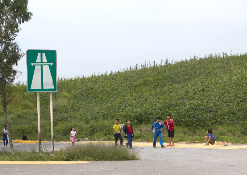 North Korean children playing in front of a highway entrance road sign near the Demilitarized Zone, North Hwanghae Province, Panmunjom, North Korea
