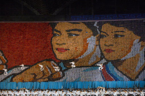 Gymnasts jumping in front of taekwando fighters made by children pixels holding up colored boards during Arirang mass games, Pyongan Province, Pyongyang, North Korea