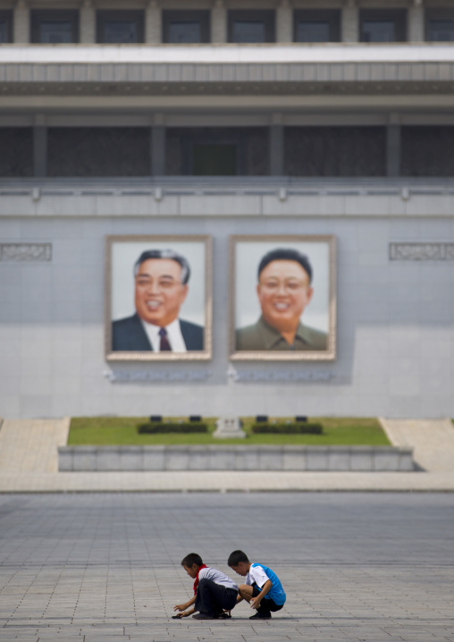 North Korean boys playing in front of Kim il Sung and Kim Jong il giant portraits on Kim il Sung square, Pyongan Province, Pyongyang, North Korea