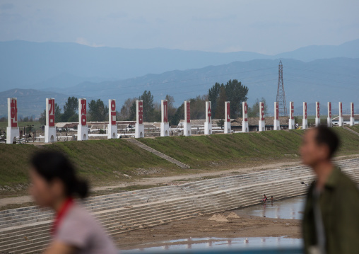 North Korean people passing in front of propaganda billboards, South Hamgyong Province, Hamhung, North Korea