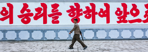 North Korean man passing in front of a propaganda billboard, North Hwanghae Province, Kaesong, North Korea
