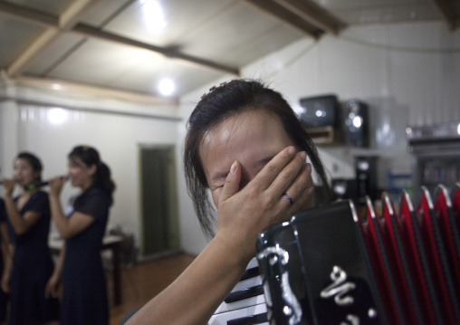 North Korean waitress with an accordion laughing in a restaurant, Pyongan Province, Pyongyang, North Korea