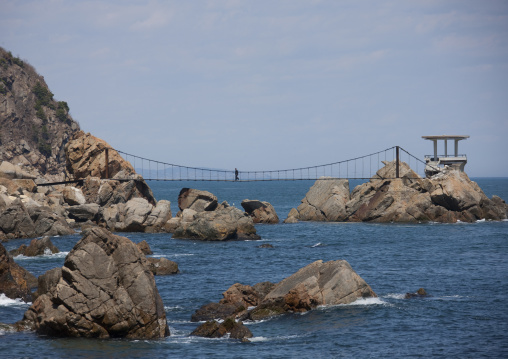 North Korean man crossing a bridge betweens rocks on the coastline, North Hamgyong Province, Chilbo Sea, North Korea